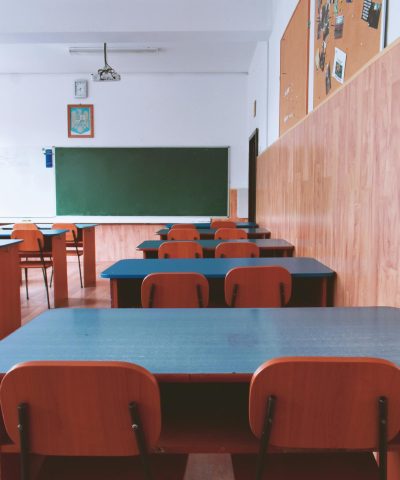 A tranquil empty classroom with wooden furniture and a green chalkboard, perfect for educational themes.