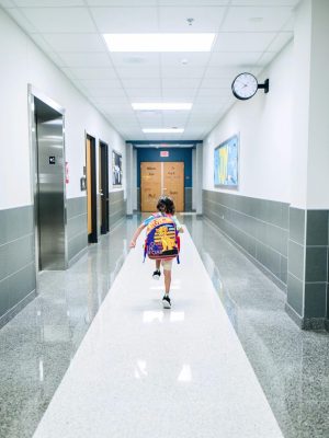 A child runs through a bright school hallway, emphasizing modern architecture and energy.
